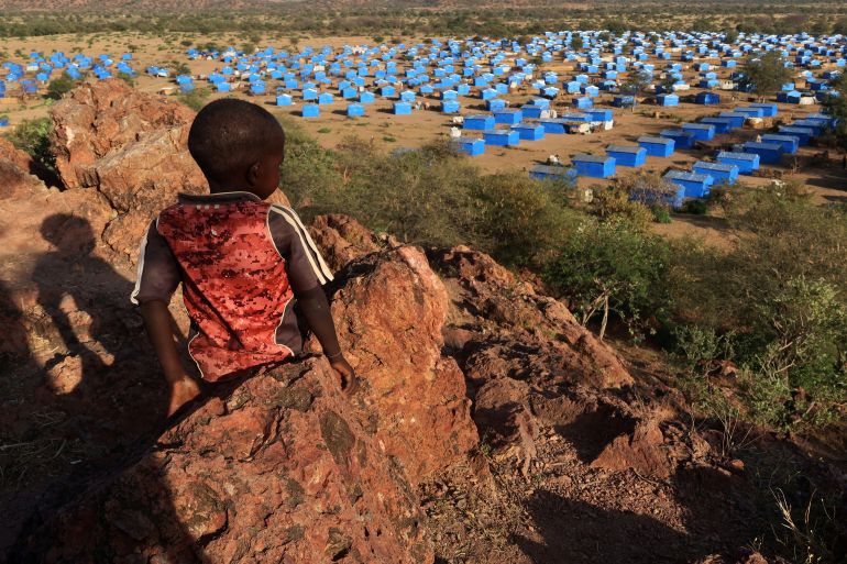 FILE PHOTO: A boy sits atop a hill overlooking a refugee camp near the Chad-Sudan border, November 9, 2023. Hundreds of Masalit families from Sudan's West Darfur state were relocated here months after fleeing to the Chadian border town of Adre, following an ethnically targeted massacre in the city of El Geneina. REUTERS/El Tayeb Siddig To match Special Report SUDAN-POLITICS/DARFUR-MALES/File Photo