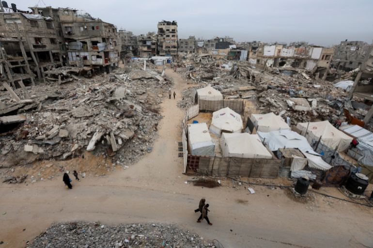 Palestinians walk past the rubble of residential buildings destroyed during the two-year Israeli offensive, in Khan Younis, southern Gaza Strip, April 15, 2026. REUTERS/Ramadan Abed