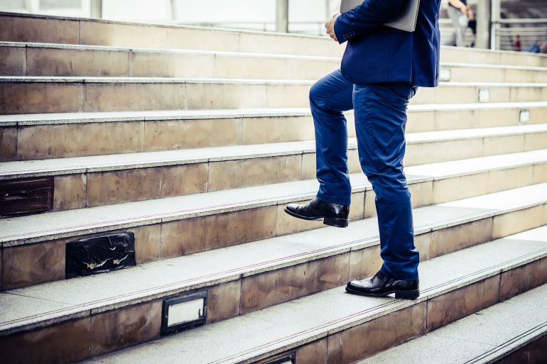 Close up of young businessman walking upstairs outside office.