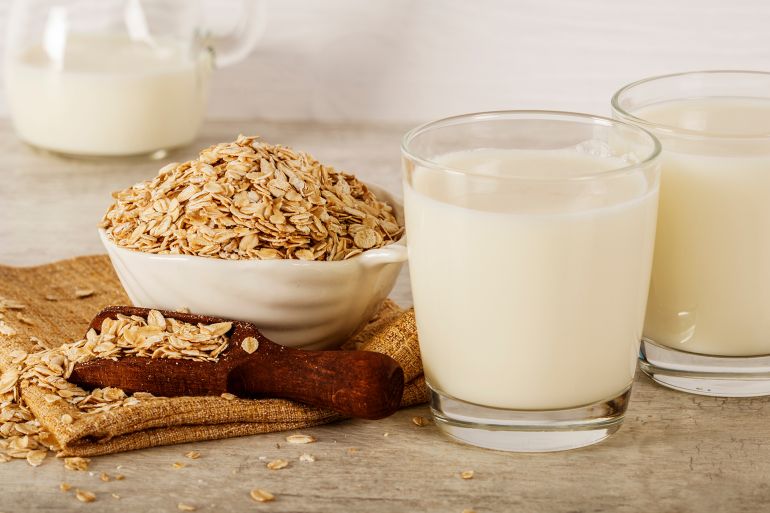 shutterstock_1934663234-1727013755 Oatmeal in a white bowl with a glass of milk on a white blue background. A healthy, nutritious morning breakfast. Oat milk. Healthy vegan non-dairy organic drink with flakes. ; Shutterstock ID 1934663234; purchase_order: aj net; job: ; client: ; other: