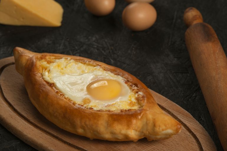 Adjarian Khachapuri – Georgian cheese bread. Baked open pie with cheese and egg yolk filling.