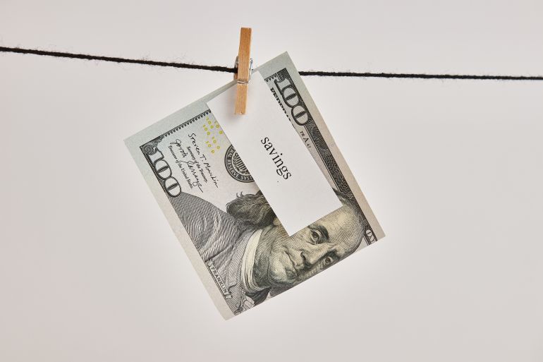 A $100 bill with the words "economy" on it hung on a clothesline.