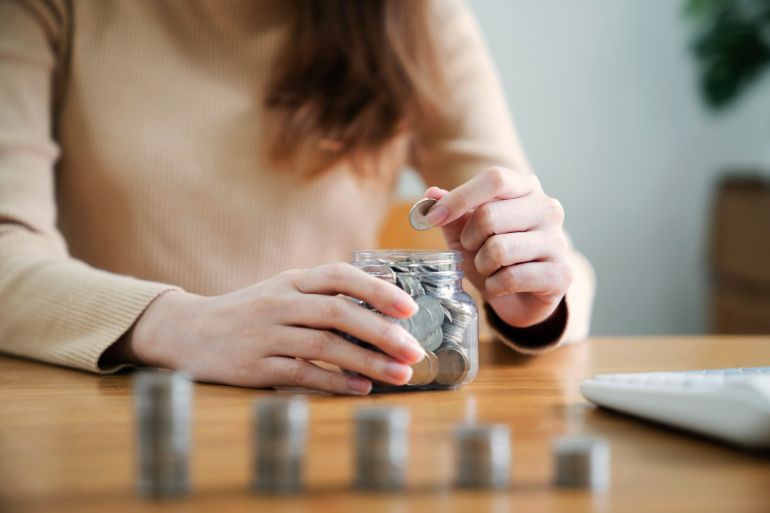 Growing savings concept. Saving money by hand putting coins money banknotes in jug glass financial accounting planning.