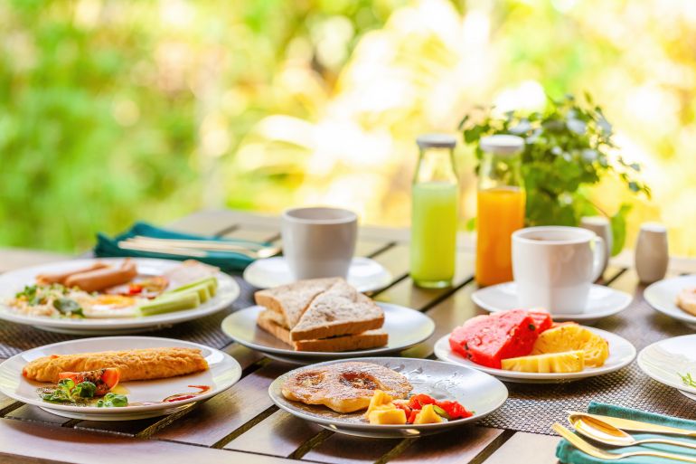 shutterstock_2332228271-1764228571 Morning breakfast at tropical outdoor restaurant in Asian resort. Enjoy a tasty and nutritious meal with ...