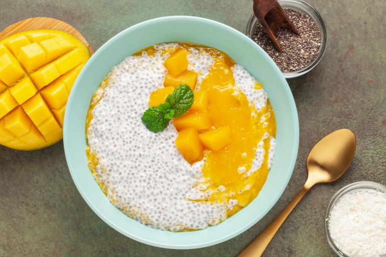 Chia seed pudding from coconut milk with mango puree and cubes in bowl. Vegan food. Clean eating concept. Top view