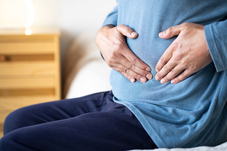 Man sitting alone on his bed and suffering from stomach cramps while home alone.Abdominal pain can be caused by digestive problems, infections, intestinal inflammation or more serious diseases.; Shutterstock ID 2569966609; purchase_order: aj; job: ; client: ; other: