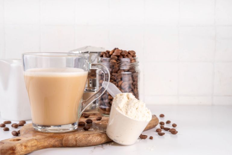 Protein coffee, whey isolate latte drink with whey protein powder in scoop and coffee beans, on kitchen table copy space