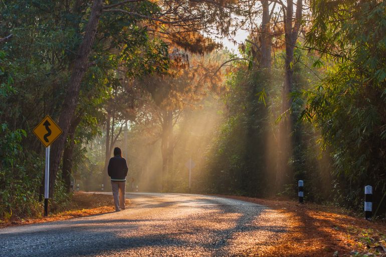 A yong women walking alone on the road sunrise