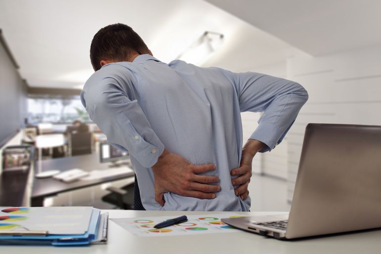 Business man with back pain an office . Pain relief concept; Shutterstock ID 572526787; purchase_order: aj; job: ; client: ; other: