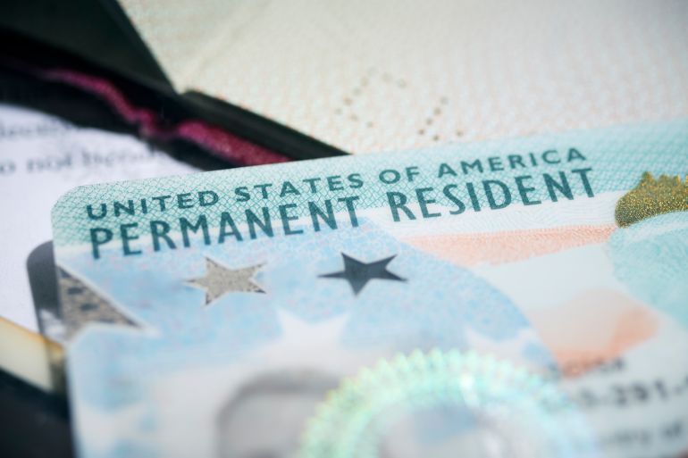 Close-up of a United States Permanent Resident Card (Green Card) placed among various official documents