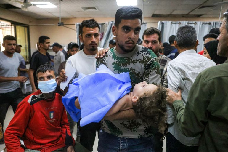 Graphic content / A man caries an injured child at the trauma ward at Nasser Medical Complex in Khan Yunis in the southern Gaza Strip on May 25, 2026. Gaza remains gripped with daily violence despite a formal ceasefire in place since October 2025, with both the Israeli military and Hamas accusing one another of violating the truce.