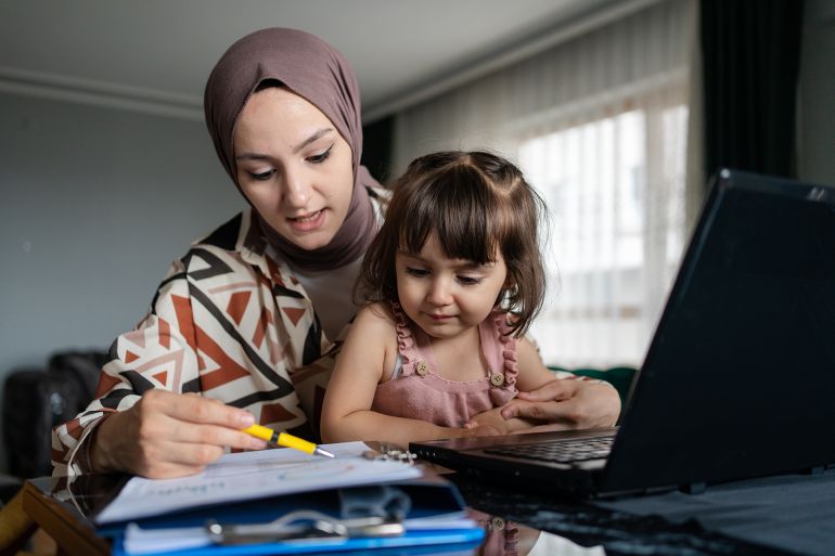 Middle Eastern mother working and spending time with baby at home