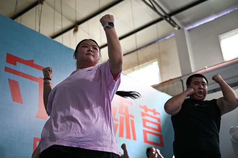 This photo taken on October 23, 2024 shows Yang Chi'ao (L) exercising at a weight loss camp in Chengdu, in China's southwestern Sichuan province. - Yang Chi'ao takes her place next to gym equipment and waits to be called by an instructor at a weight-loss camp in China, where over half of adults are overweight. Boasting strict daily exercise regimens, mandatory trips to the scale and rigid surveillance to guard against snacking, the facilities have popped up across China as it grapples with a growing obesity crisis. (Photo by Hector RETAMAL / AFP) / TO GO WITH 'CHINA-HEALTH-OBESITY, FOCUS' BY ISABEL KUA