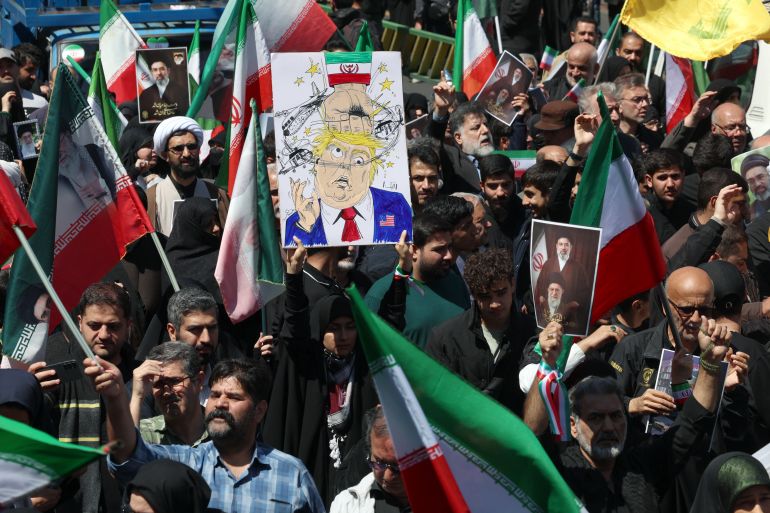 A woman holds a poster mocking US President Donald Trump while others hold portraits of Iran's slain supreme leader Ayatollah Ali Khamenei and his son and successor Mojtaba Khamenei during a rally to commemorate his death in Tehran on April 9, 2026.