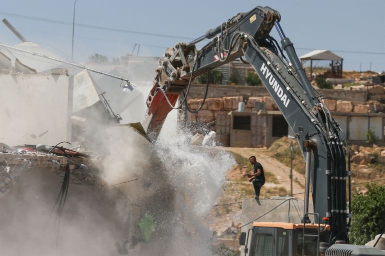afp_69f9e17eb5be-1777983870-1 A Palestinian man watches while an excavator demolishes a Palestinian house that was built without a permit, in the village of al-Dirat near Yatta town in the occupied West Bank city of Hebron, on May 4, 2026.