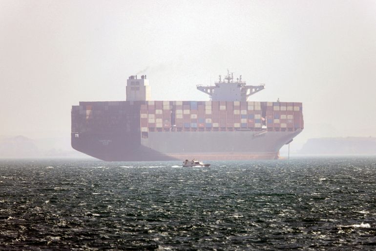 TOPSHOT - In this picture obtained from Iran's ISNA news agency and taken on May 2, 2026, the Iran-flagged container vessel Hamouna is pictured while anchored as a small motorboat passes by, in the Strait of Hormuz off Bandar Abbas in southern Iran.