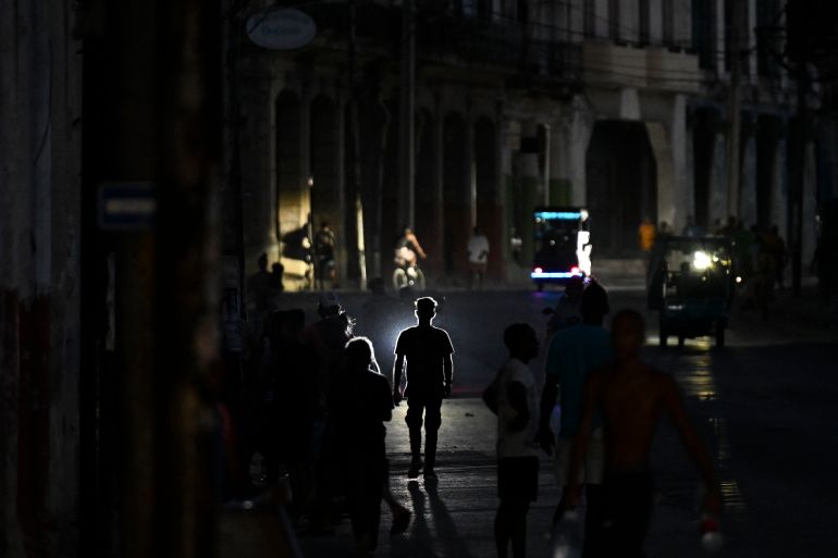 afp_6a056409468a-1778738185-1 TOPSHOT - People walk on a street during a blackout in Havana on May 13, 2026.