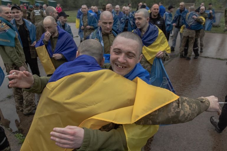 afp_6a06e47e3575-1778836606 Released Ukrainian prisoners of war (POWs) wrapped with Ukrainian national flags hug each other following a prisoner exchange at an undisclosed location, in the Chernihiv region on May 15, 2026, amid the Russian invasion of Ukraine.