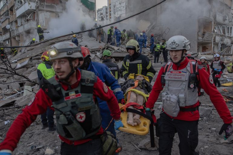TOPSHOT - Rescuers carry an injured person at the site of a residential building that was partially destroyed following Russian drones and missiles strikes in Kyiv on May 14, 2026, amid the Russian invasion in Ukraine.