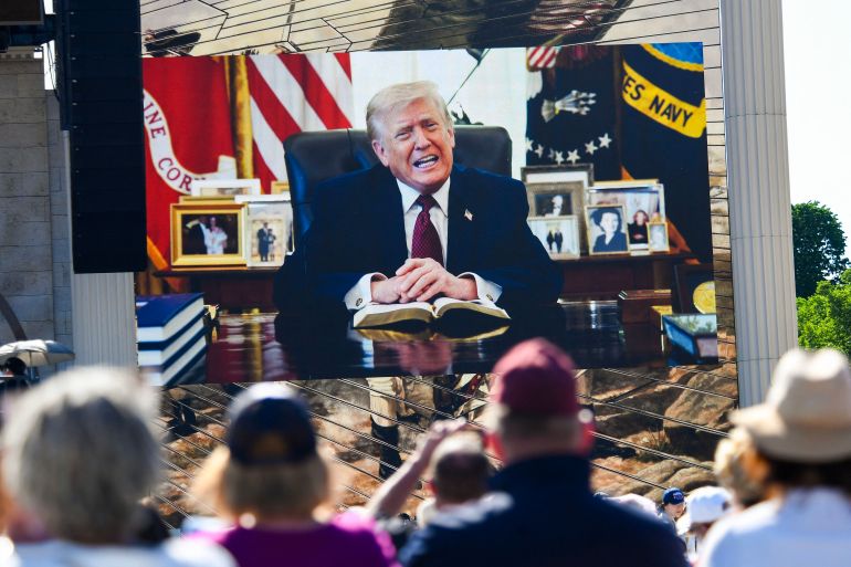 Attendees watch a pre-recorded video of US President Donald Trump reading from the Bible during "Rededicate 250: A National Jubilee of Prayer, Praise and Thanksgiving" on the National Mall in Washington, DC, on May 17, 2026.