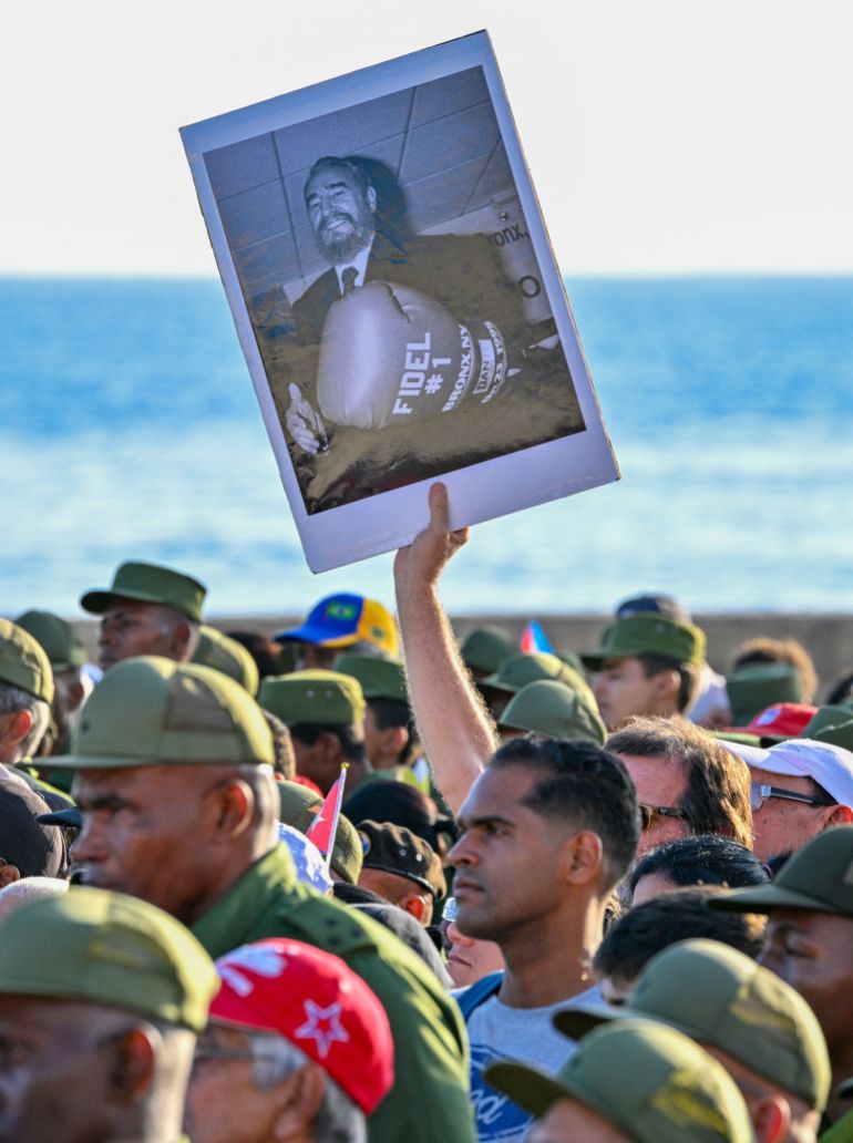 A person holds a photograph of former Cuban president Fidel Castro during a rally in support of former Cuban president Raul Castro, 94, who has been indicted by a US court, outside the US Embassy in Havana on May 22, 2026. (Photo by ADALBERTO ROQUE / AFP)