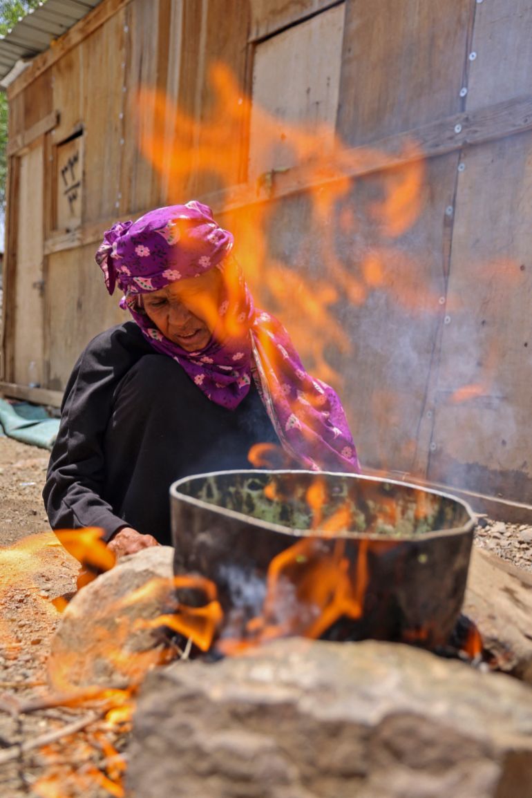 afp_6a13339c61da-1779643292 Displaced Yemeni woman Saeedah Mohammed boils tree leaves to feed her grand-children outside their makeshift tent in the Al-Manij displacement camp, near the city of Taez in Yemen's southwest, on May 21, 2026.