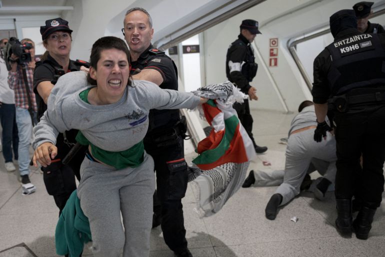 afp_6a1354264511-1779651622 Basque police officers detain a member of the Global Sumud Flotilla upon their arrival at Bilbao airport on May 23, 2026.