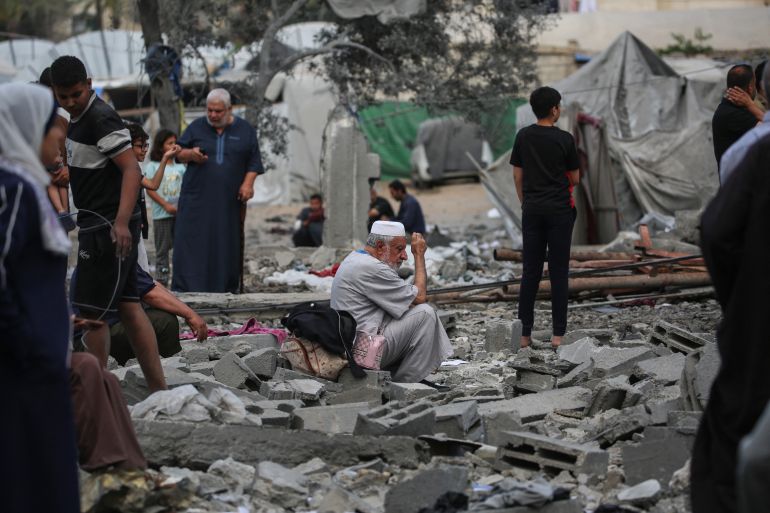 A Palestinian man sits on the rubble at the site of a residential building targeted overnight by an Israeli strike, following a warning from the Israeli military to evacuate, in Deir el-Balah in the central Gaza Strip, on May 24, 2026.