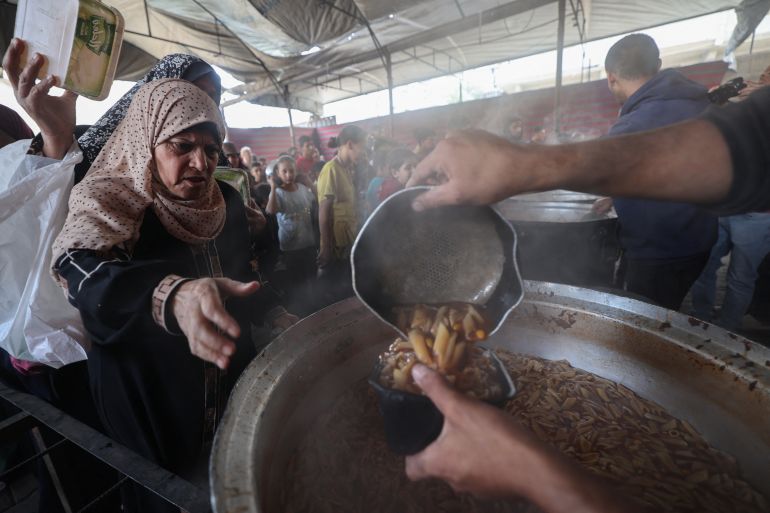 afp_6a15b0c09fcc-1779806400 Displaced Palestinians receive food from a charity kitchen at the Nuseirat refugee camp in the central Gaza Strip on May 21, 2026.