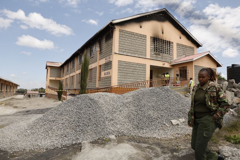 afp_6a1896d82d17-1779996376 CORRECTION / TOPSHOT - A Kenyan police officer walks past forensic experts standing near the entrance of a building at Utumishi Girls Academy where a deadly fire took place in Gilgil, north of the capital Nairobi on May 28, 2026.