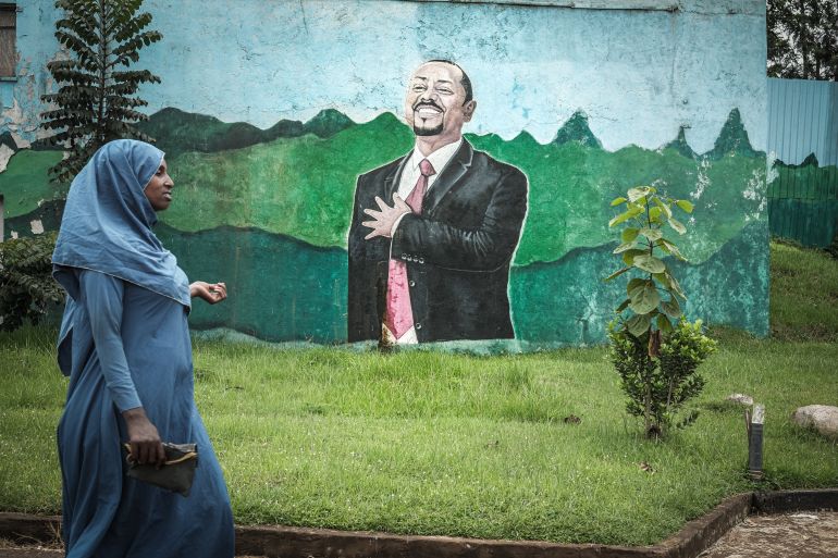 afp_6a1c25325cdd-1780229426 TOPSHOT - A woman walks past a large mural depicting Ethiopian Prime Minister Abiy Ahmed in Agaro, a town in the constituency where the Ethiopian leader is running for office in the June 1 general election, in Oromia region, on May 28, 2026. (Photo by Marco Simoncelli / AFP)