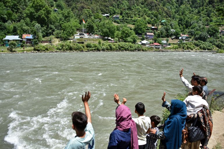 afp_6a1c4f0a4fd3-1780240138 This photograph taken on May 29, 2026 shows family members of Raja Liaqat, who died last month in Keran village on the Indian-administered side of Kashmir, standing along the banks of the Neelum River and waving to their relatives across the Line of Control in Indian-administered Kashmir, as seen from Keran village in Pakistan-administered Kashmir.