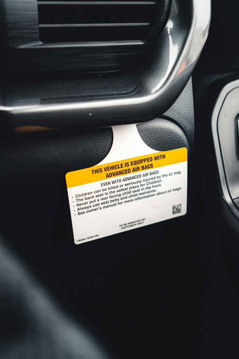 alwsadat-alhwayyt-1778935832 Detailed view of a car airbag safety warning label inside a vehicle.