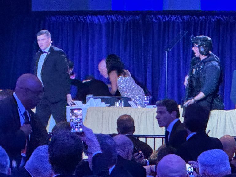 U.S. Secret Service agents surround President Donald Trump as he is taken from the stage after a shooting incident outside the ballroom during the White House Correspondents Dinner, Saturday, April 25, 2026, in Washington. (AP Photo/Mark Schiefelbein)