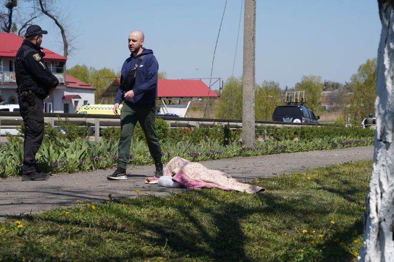 A resident walks past the body of a victim following a Russian missile attack in Merefa, Kharkiv region, Ukraine, Monday, May 4, 2026. (AP Photo/Andrii Marienko)