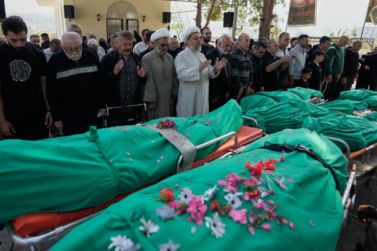Men pray over the bodies of people killed a day earlier in an Israeli airstrike in the village of Saksakieh, as flowers are scattered over the shrouds during a funeral procession in the southern port city of Sidon, south Lebanon, Sunday, May 10, 2026. (AP Photo/Mohammed Zaatari)