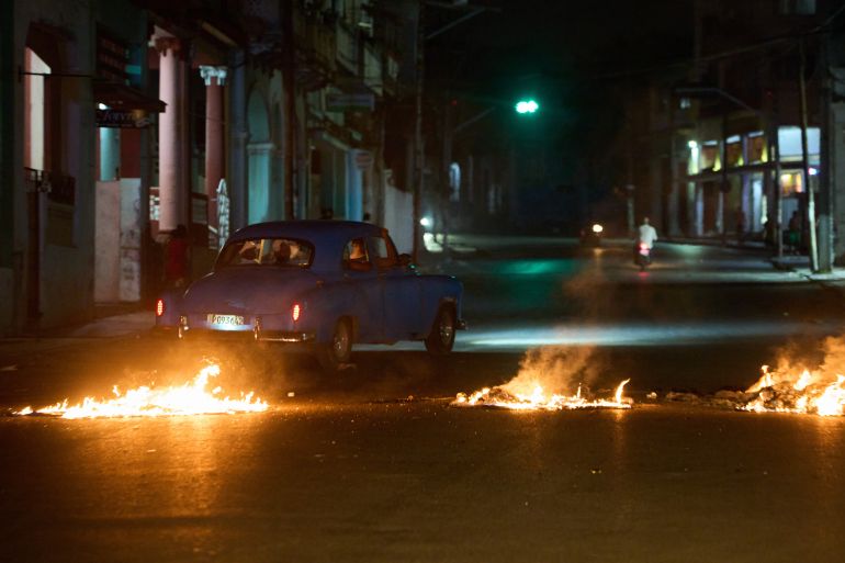 ap_6a05668bb277e-1778738827 People drive a classic American car through a barricade set up by residents protesting against prolonged power outages in Havana, Cuba, Wednesday, May 13, 2026. (AP Photo/Ramon Espinosa)