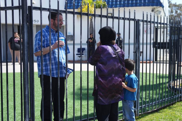 Imam Taha Hassane speaks with a woman who did not want to be identified and her child outside of the Islamic Center of San Diego, the day after a shooting, Tuesday, May 19, 2026, in San Diego. (AP Photo/Jae C. Hong)