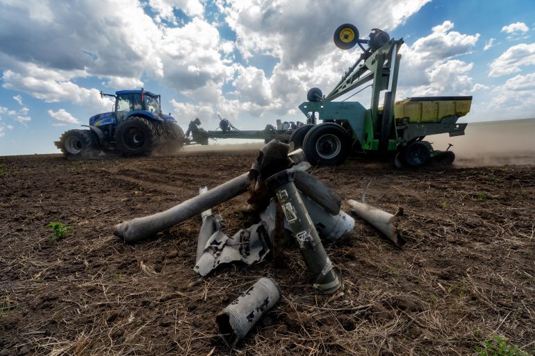Fragments of Russian missiles lie on the field against the background of the working farmers near the front line in the Kharkiv region, Ukraine, Friday, May 22, 2026. (AP Photo/Andrii Marienko)