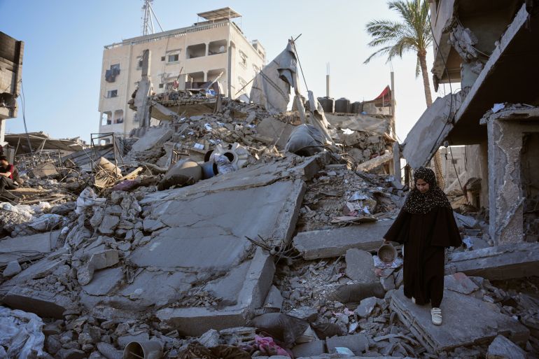 A Palestinian woman walks through the rubble of the Al-Kurd family home, destroyed in an Israeli airstrike in Deir al-Balah, central Gaza Strip, Sunday, May 24, 2026. (AP Photo/Abdel Kareem Hana)