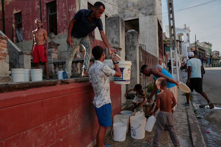 People fill containers with water outside a building in Havana, Monday, May 25, 2026. (AP Photo/Jorge Luis Banos)