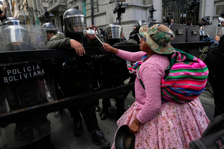 A demonstrator points her ladle at police standing guard near the government palace during an anti-government protest in La Paz, Bolivia, Wednesday, May 27, 2026. (AP Photo/Juan Karita)