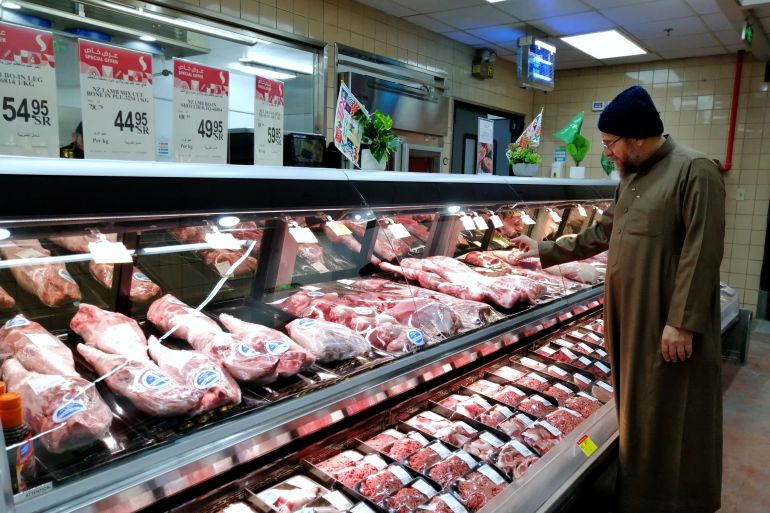 Al Ahsa Saudi Arabia March 2023, an arab male customer wears winter thoub and hat picking fresh meat products at Tamimi Market. ; Shutterstock ID 2269674353; purchase_order: aljazeera ; job: ; client: ; other: