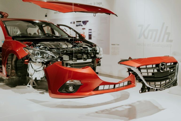 bracabet-akhtracabf-1778935571 Explore a detailed view of a partially disassembled red Mazda 3 showcased at an auto exhibition.