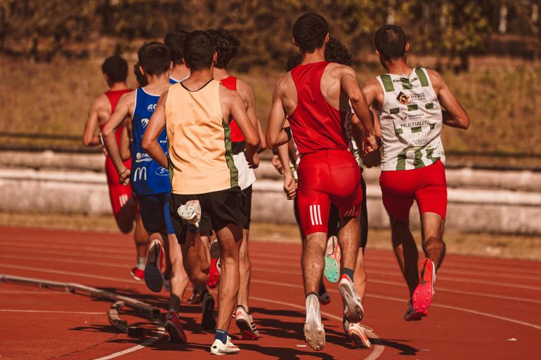 Men competing in a running event on a sunny outdoor track, showcasing athleticism and determination.