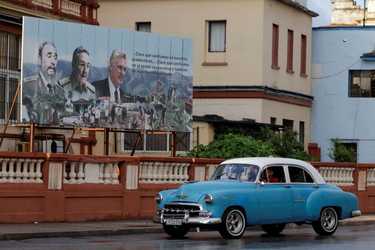 A vintage car passes by images of late Cuban President Fidel Castro, Cuba's former President Raul Castro and Cuba's President Miguel Diaz-Canel displayed on a billboard in Havana, Cuba, May 15, 2026. REUTERS/Norlys Perez TPX IMAGES OF THE DAY