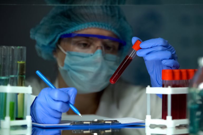 Doctor checking tube with blood analysis and making notes, lymphoma cancer
