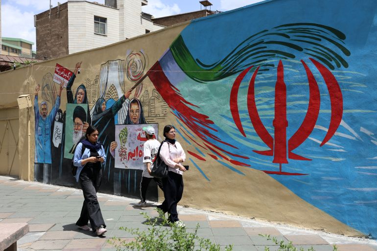 epa12940978 Iranians walk next to a anti-US and Israel mural in a street in Tehran, Iran, 08 May 2026. Iran and US exchanged fire in the Strait of Hormuz amid a ceasefire. EPA/ABEDIN TAHERKENAREH