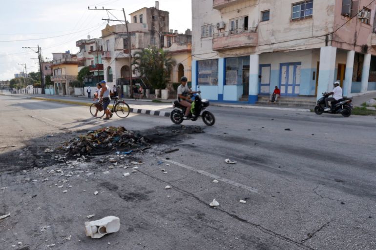 epa12957792 People walk past a garbage container burned the night before in protest against the prolonged blackouts in Havana, Cuba, 14 May 2026. The Cuban government acknowledged that the situation of the National Electric System (SEN) is 'critical', with blackouts in Havana exceeding 22 hours a day in recent days, while in other provinces the outages have lasted two consecutive days. EPA/Ernesto Mastrascusa