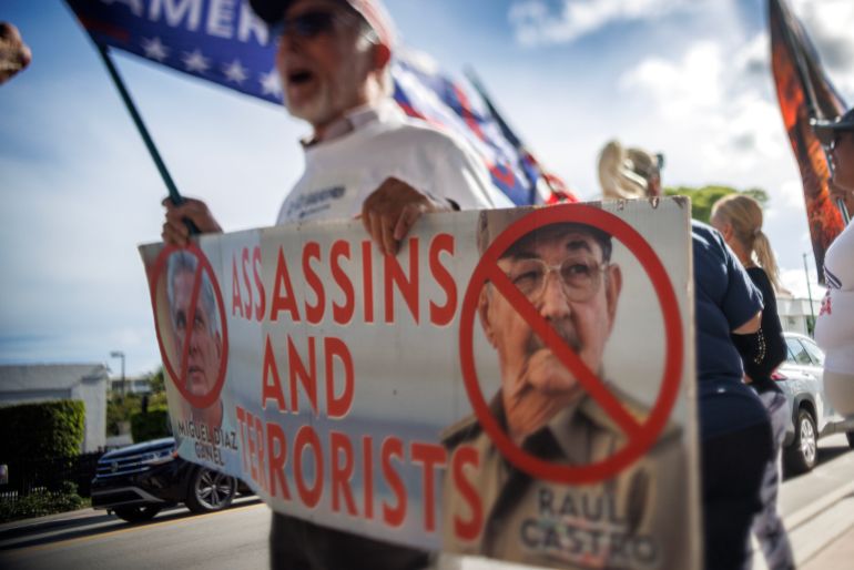 epaselect epa12979664 A Cuban in exile holds up a sign that reads 'Assassins and terrorists' as they celebrate Cuba's Republic Day in Miami, Florida, USA, 20 May 2026. The date marks the formal establishment of the Republic of Cuba in 1902. This year's celebrations coincide with US prosecutors unsealing an indictment against former Cuban President Raul Castro over the 1996 shootdown of two civilian aircraft operated by Brothers to the Rescue. EPA/CRISTOBAL HERRERA-ULASHKEVICH